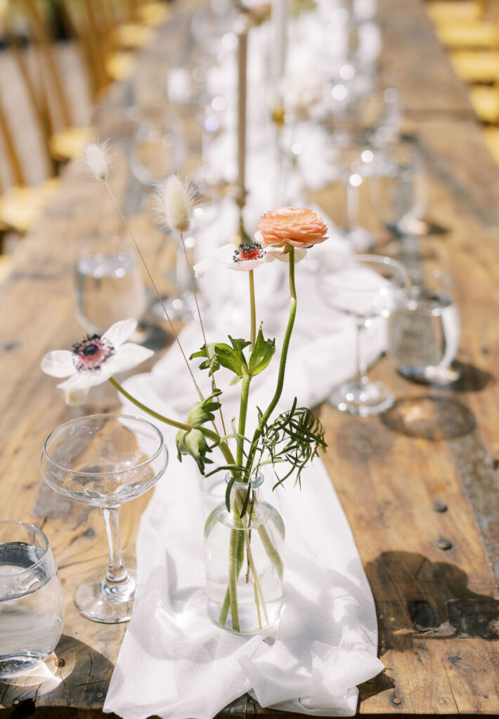Flowers in bud vases on wooden table at wedding reception